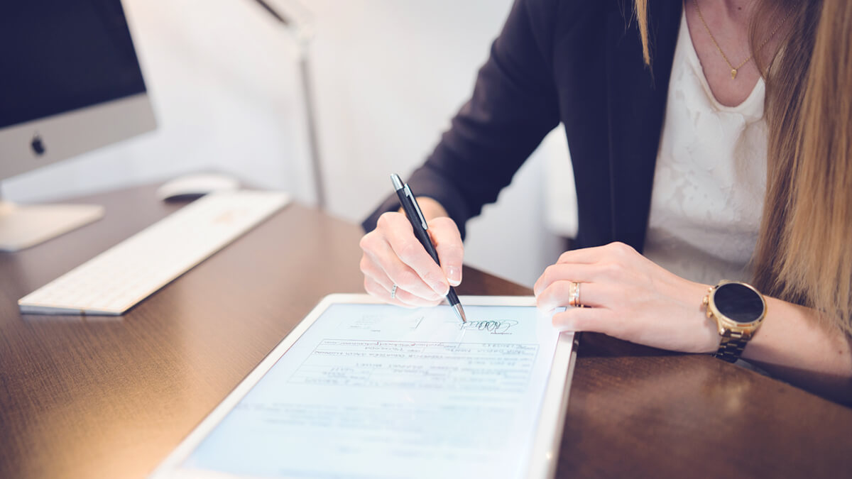 Eine Psychotherapeutin unterzeichnet einen digitalen Behandlungsvertrag auf einem Tablet in ihrer Praxis.