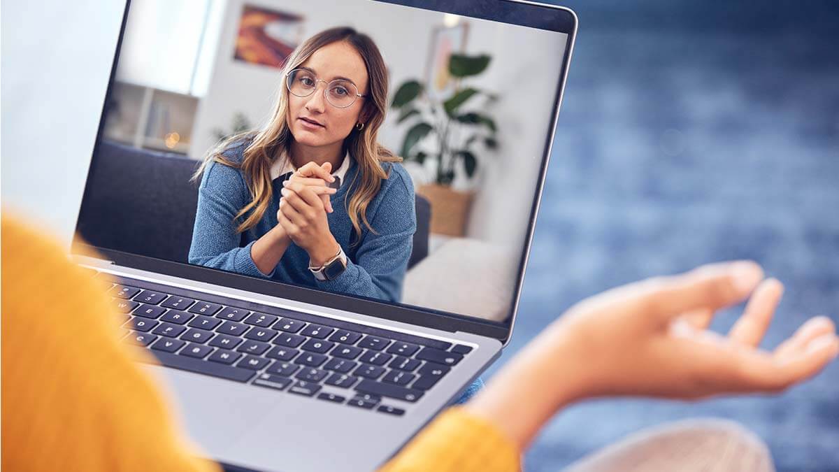 In einer Videosprechstunde unterstützt eine Frau per Laptop Menschen bei Fragen zu ihrer mentalen Gesundheit. Die virtuelle Psychologin oder Therapeutin bietet Rat und Hilfe in einem Online-Meeting, indem sie auf den Bildschirm blickt und auf Fragen des Patienten eingeht.
